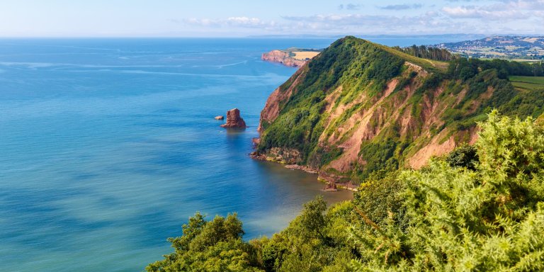 Scenic view of Jurassic Coast cliffs overlooking the sea under a clear blue sky.